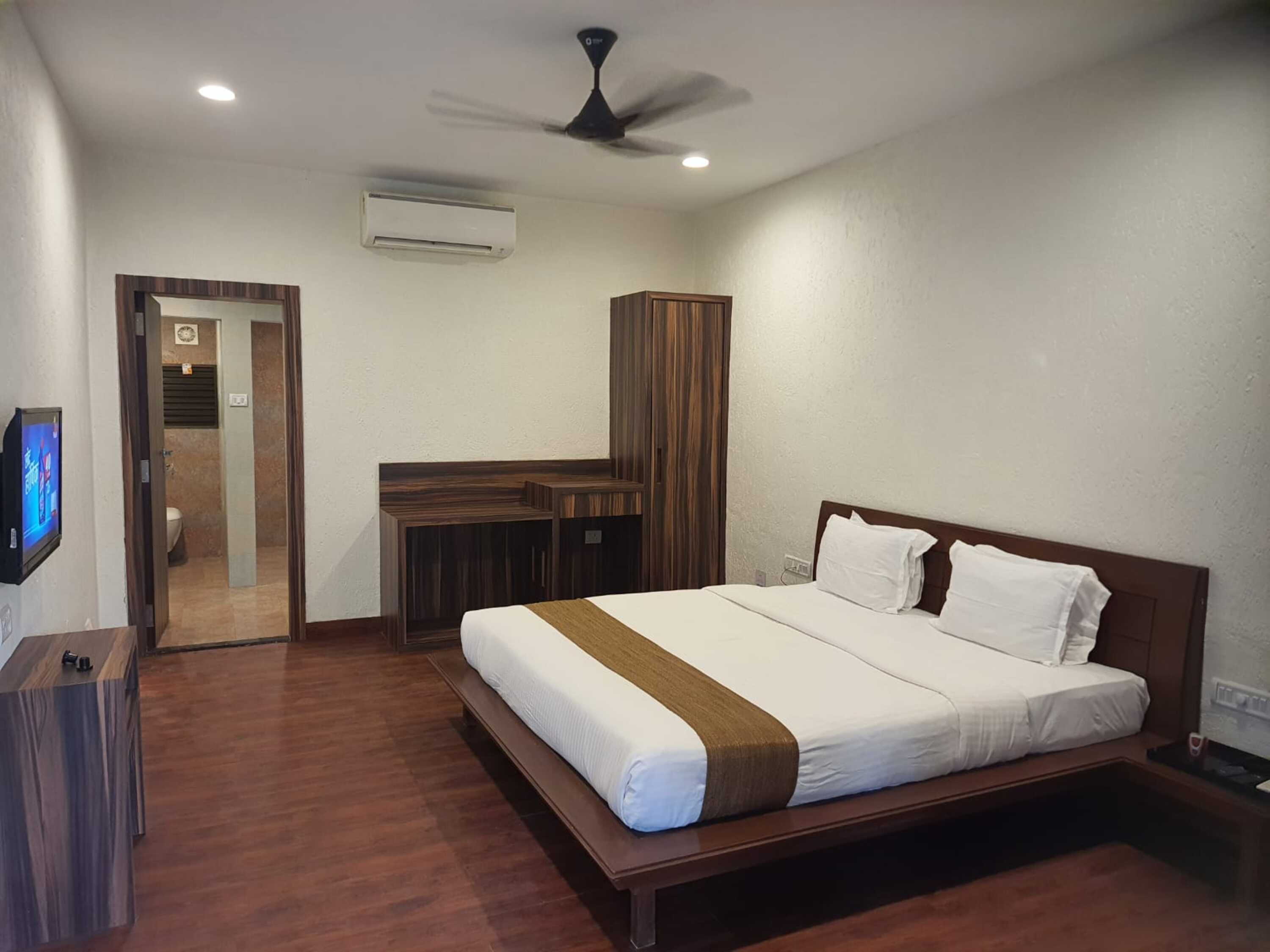 Una habitación de hotel con cama, escritorio y armario.