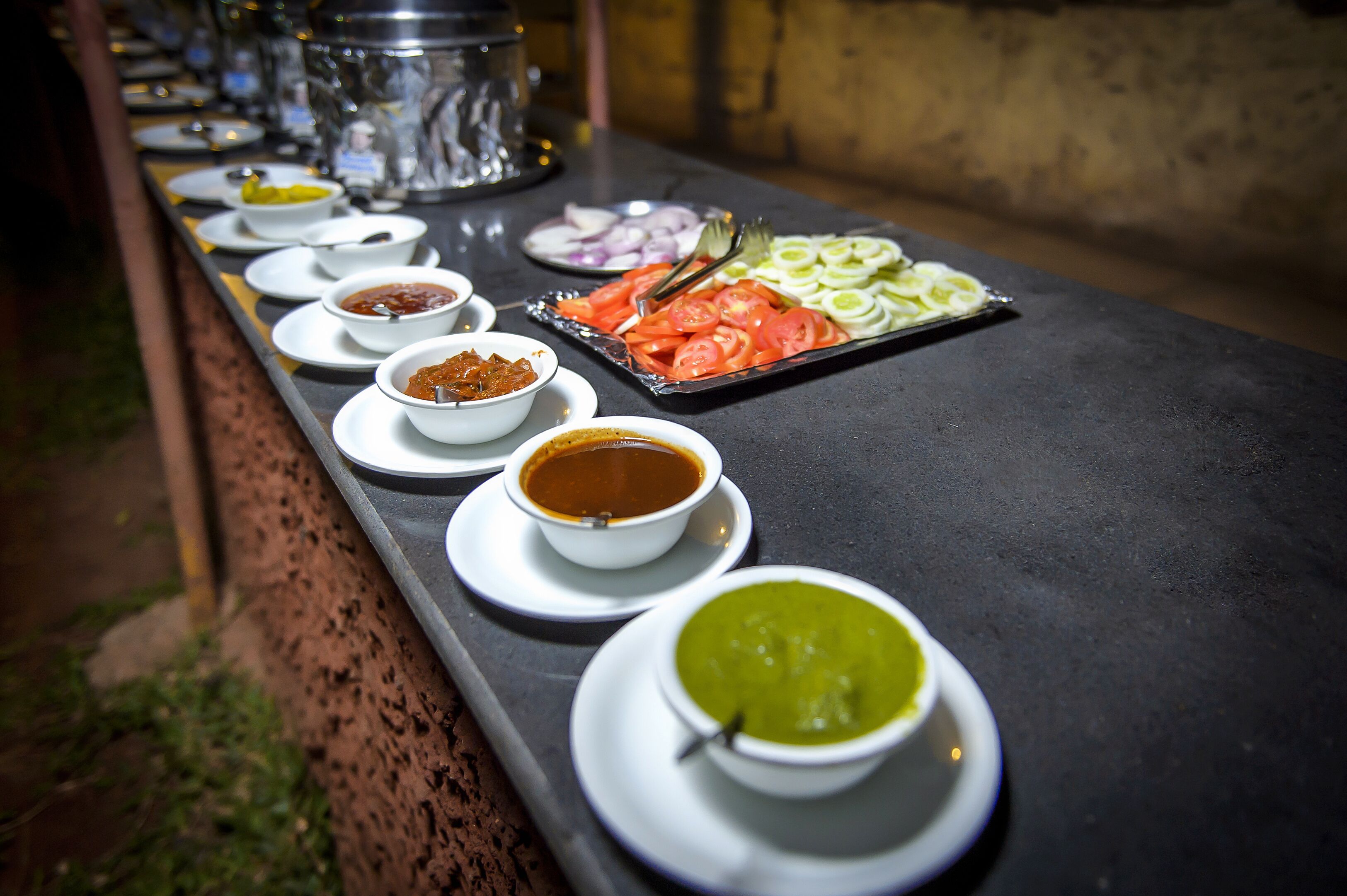 A buffet table with various dishes and condiments.
