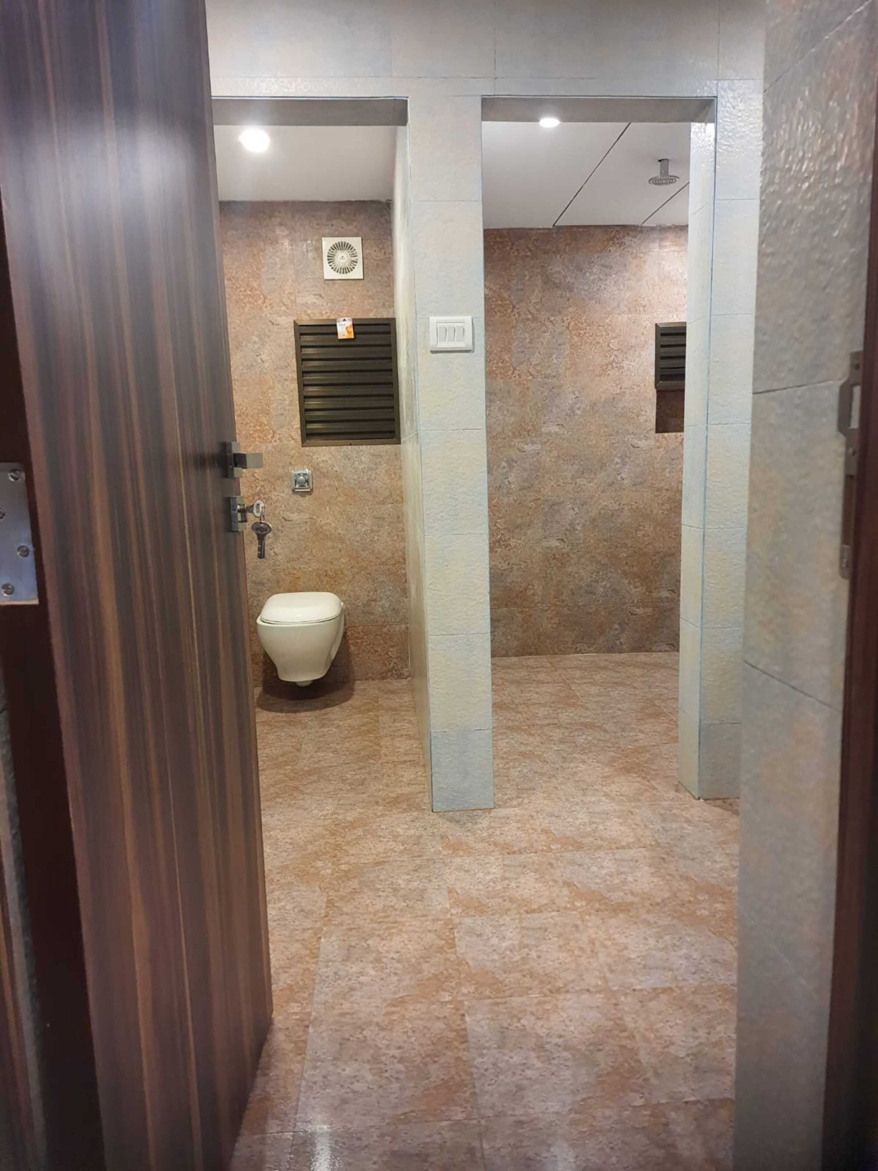 A bathroom with a toilet, shower, and a mirror.