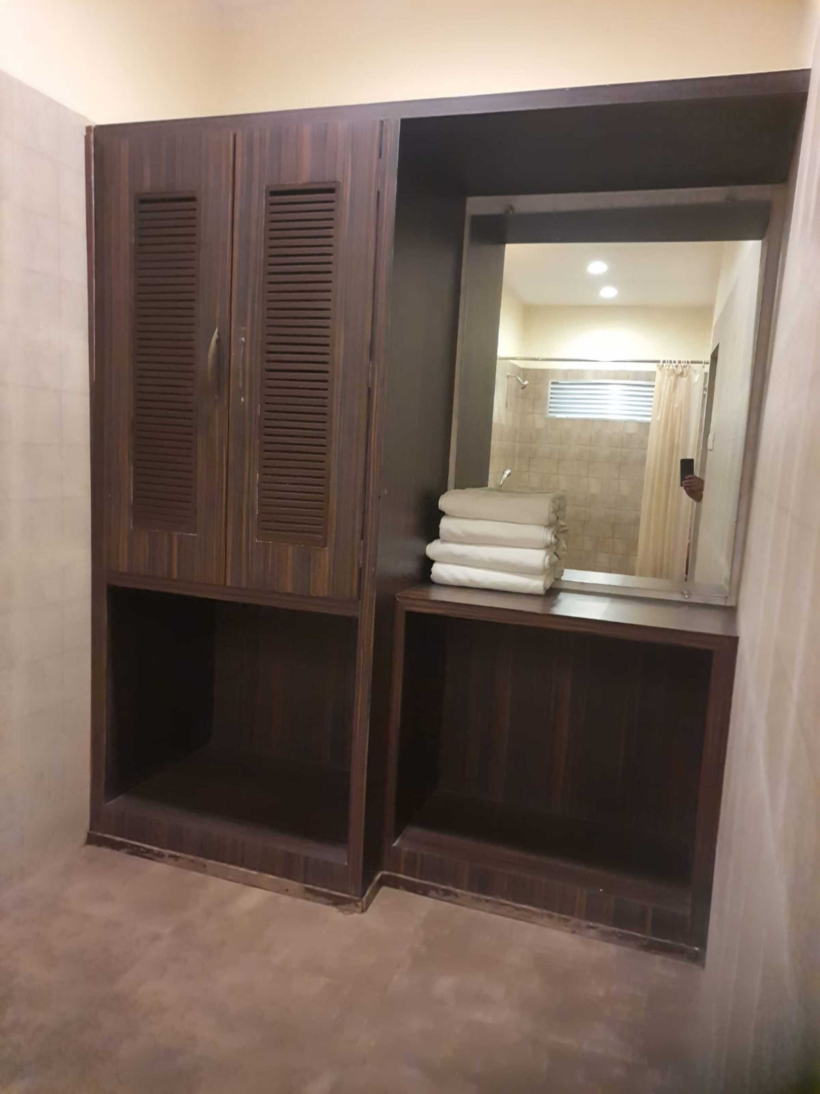 Un baño con un armario de madera, un espejo y una pila de toallas.