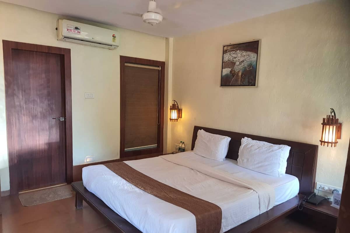 Habitación de hotel con una cama grande, un equipo de aire acondicionado, una puerta y un aplique en la pared.
