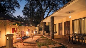 A courtyard with a swing set, a table with chairs, and a lamp post. - Adamo The Village (Karjat)
