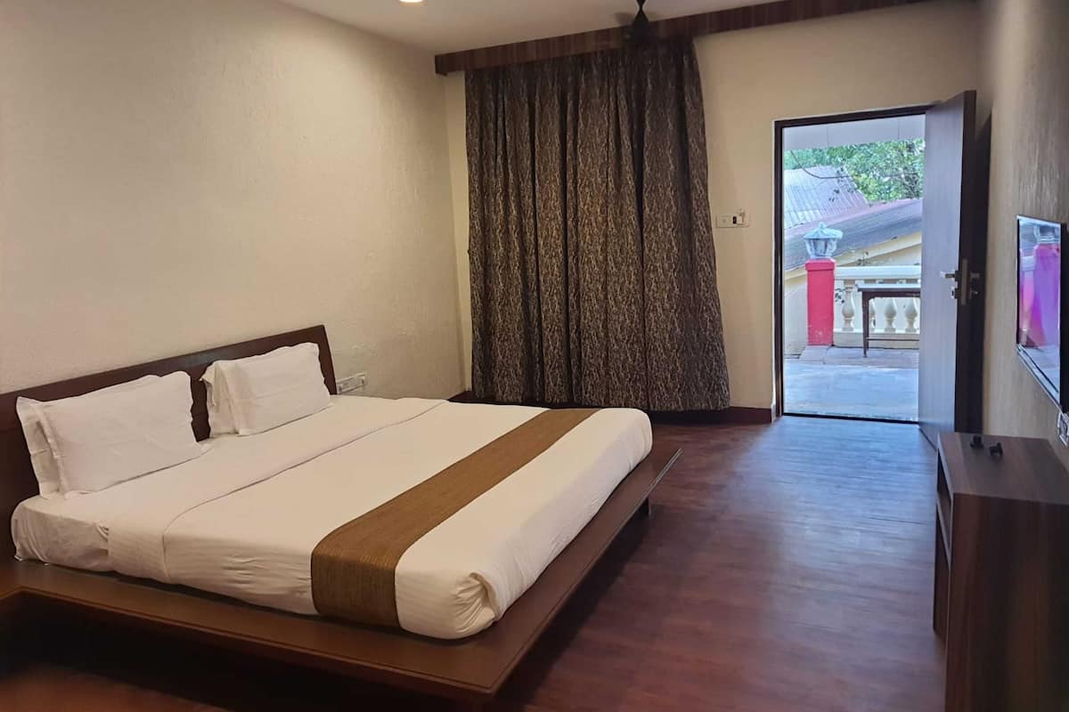 Habitación de hotel con una cama grande, un ventilador de techo y vistas al exterior a través de un ventanal.