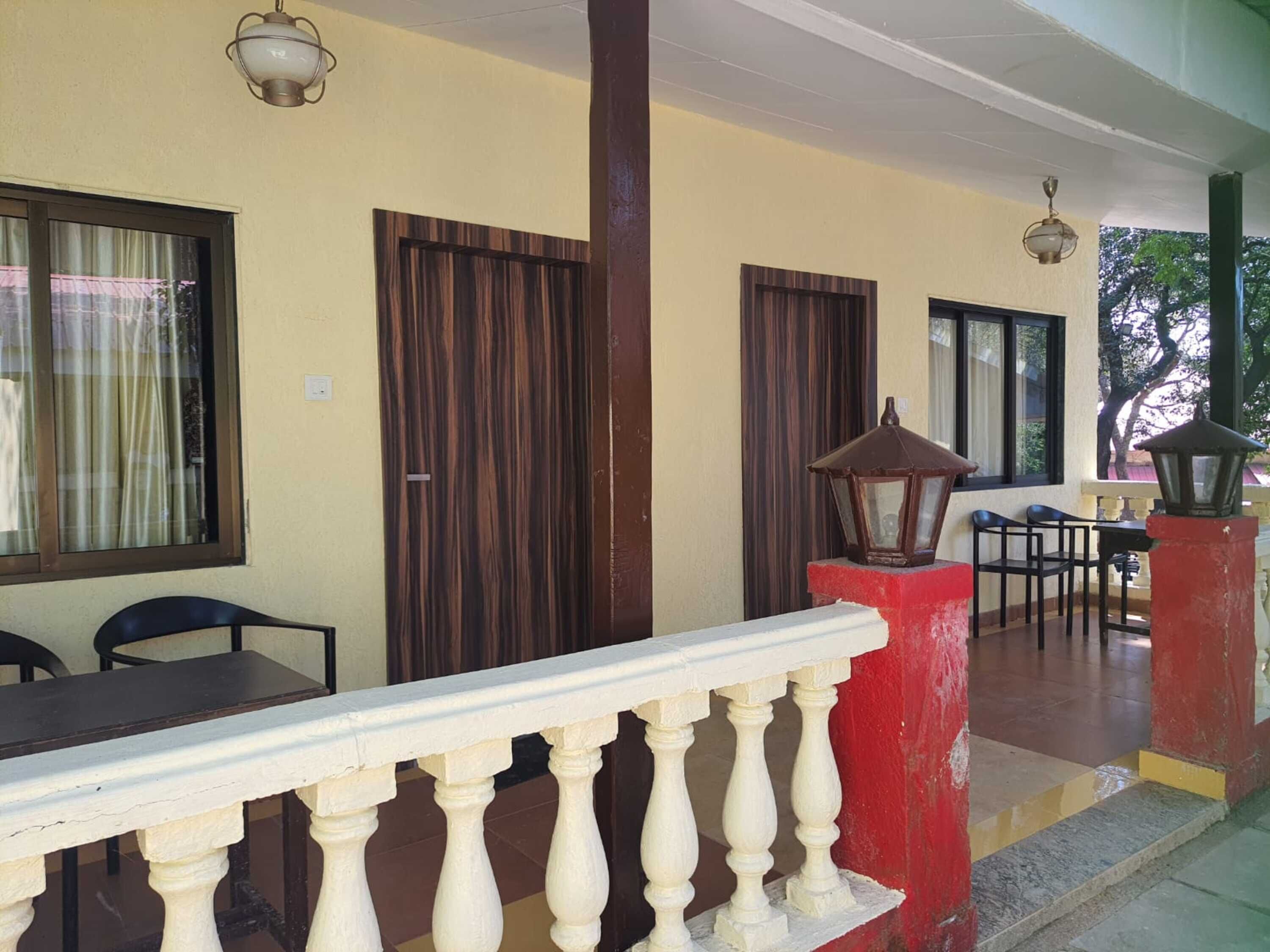 Un espace extérieur abrité, doté d’une balustrade blanche, de portes en bois et d’une table avec des chaises.