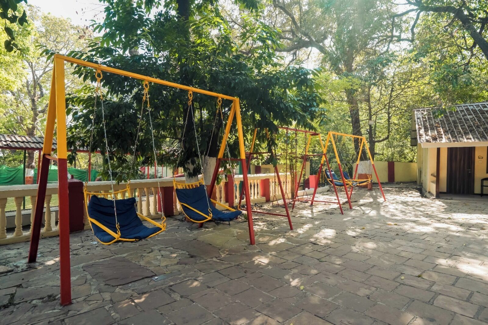 Un parque infantil con columpios y un edificio pequeño al fondo.