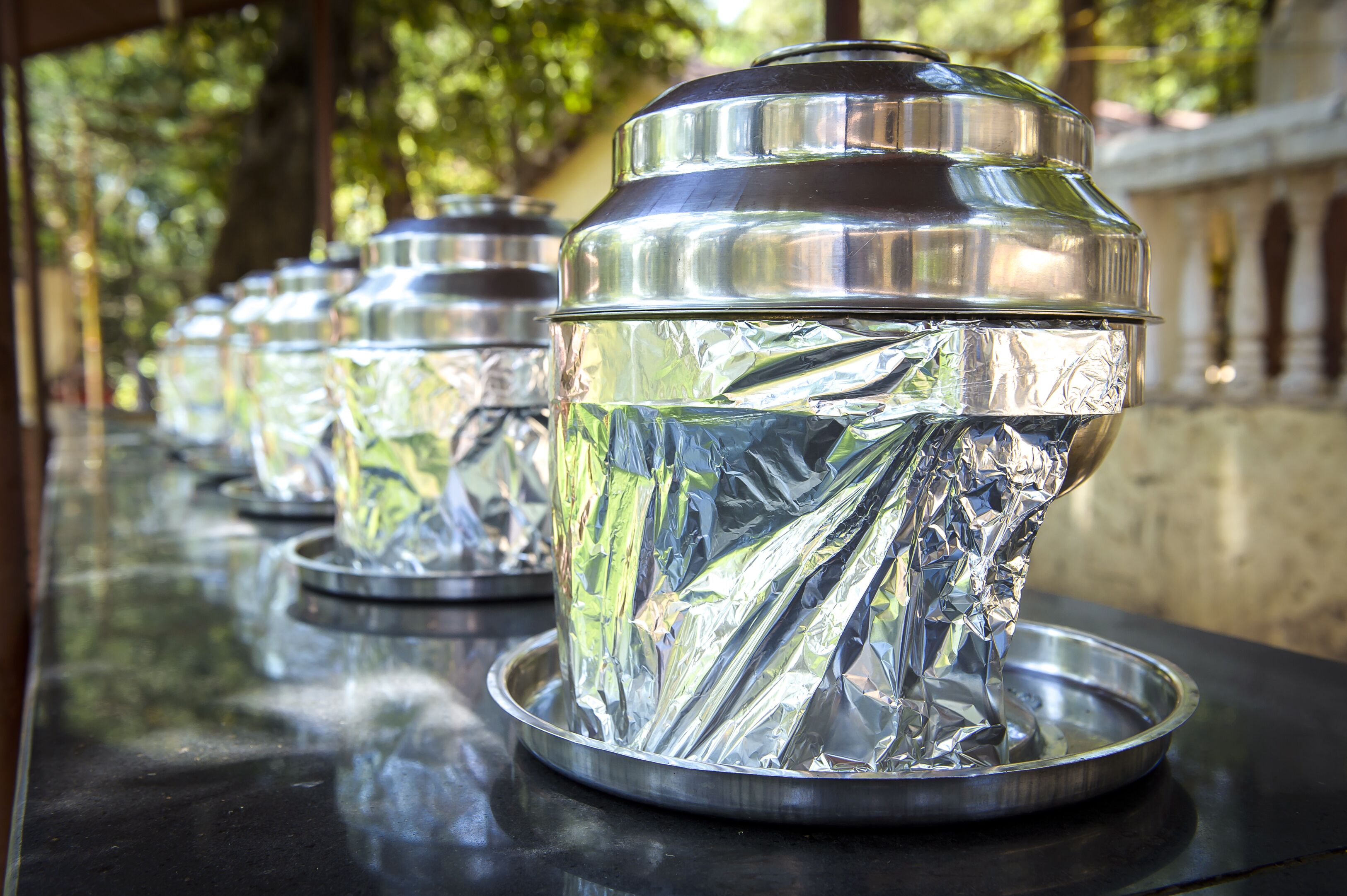 A row of metallic containers with reflective surfaces on a table.