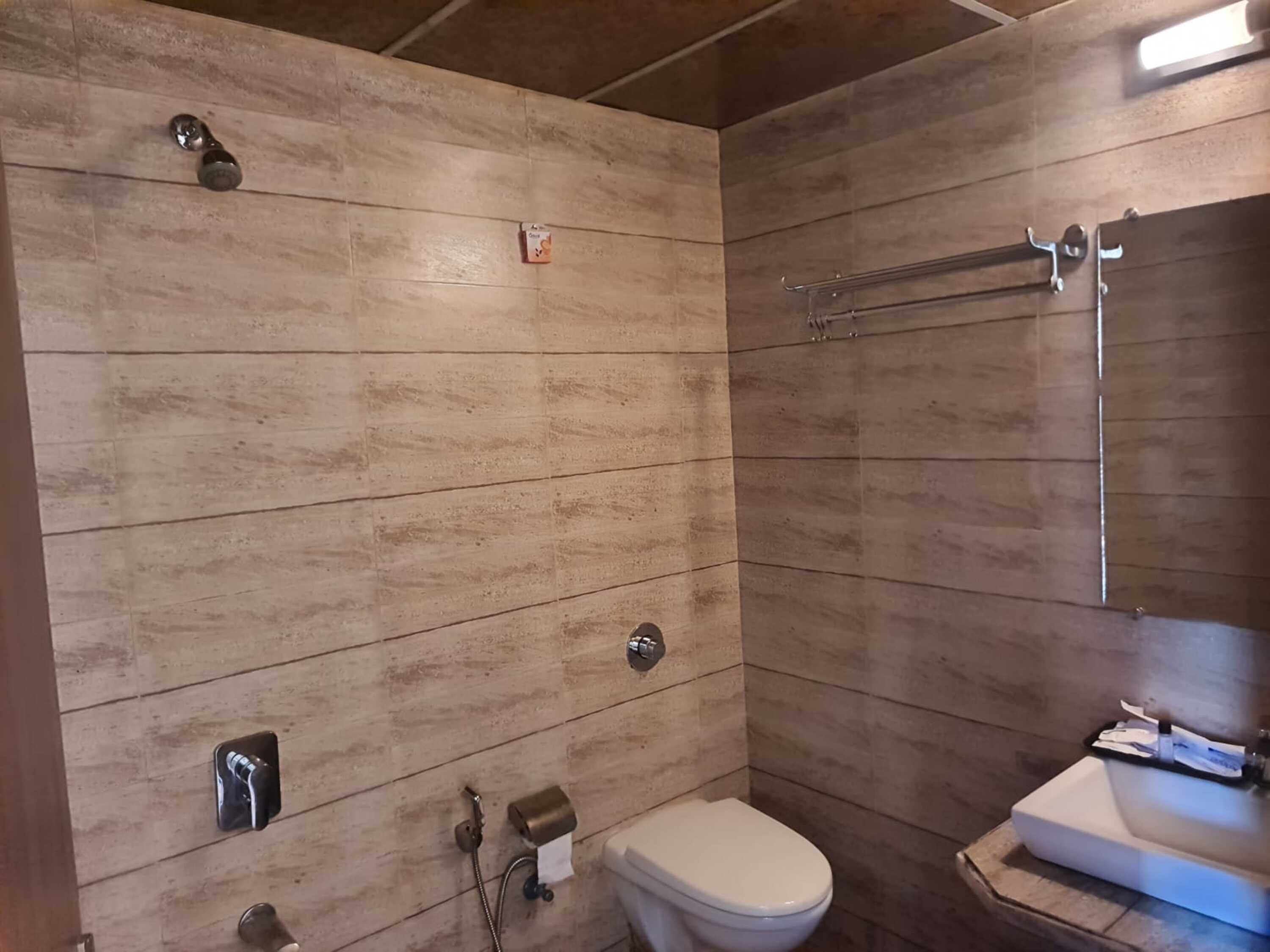 Un bagno con pareti rivestite in legno, un WC bianco, un lavabo e una doccia.