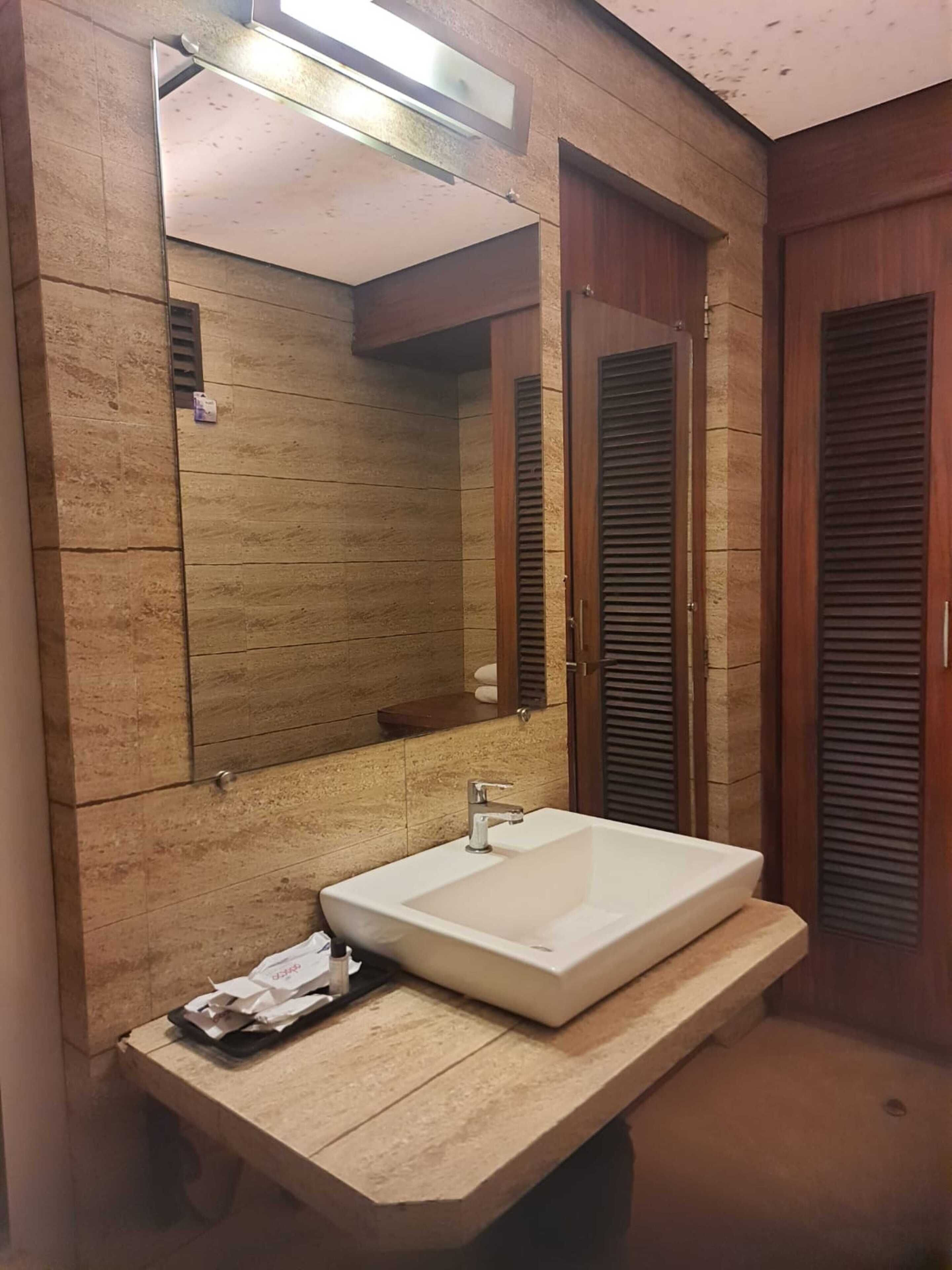A bathroom with a large mirror, a white sink, and wooden cabinets.