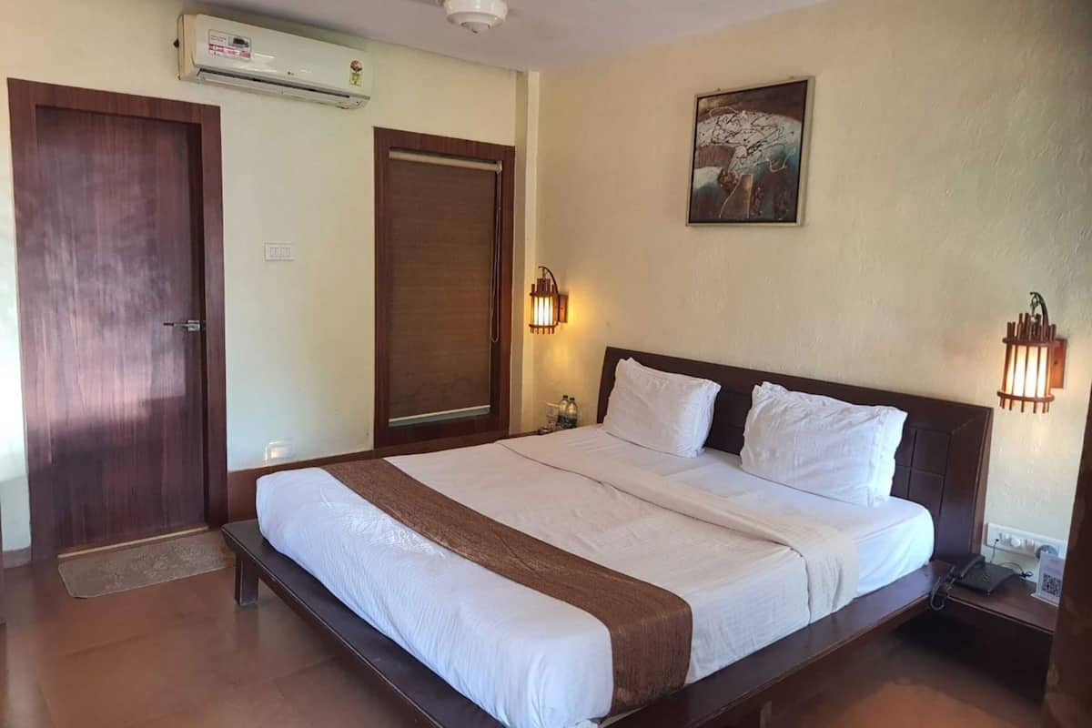 Una habitación de hotel con una cama grande, un equipo de aire acondicionado, una puerta y una lámpara fijada a la pared.