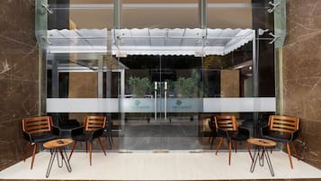 A reception area with a glass door, two wooden chairs, a small round table, and a tiled floor.