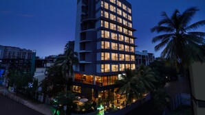 A multi-story hotel with illuminated windows, a pool area, and palm trees. -  Lemon Tree Hotel, Kalina BKC, Mumbai (Mumbai)