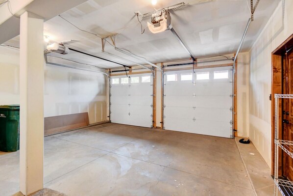 A garage with two white doors, a concrete floor, and visible electrical wiring.