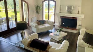 A spacious living room with a fireplace, comfortable seating, and large windows offering a view of the outdoors. - Villa Monti: Luxury Villa, Large Pool, Air Con, Amazing Views (Menton)