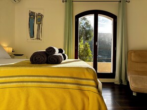 A hotel room with a bed, a set of towels, a painting on the wall, and a view through the door. - Villa-Monti, Menton, Côte d'Azur (Menton)