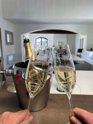 Two champagne flutes filled with champagne, a bottle of champagne, and a bucket with a red bow on a table in a modern kitchen setting. - Villa-Monti, Menton, Côte d'Azur (Menton)