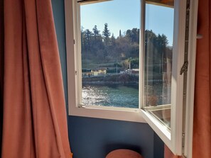 A room with a window overlooking a body of water and a forested area.