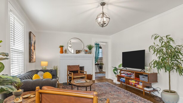 A living room with a sofa, armchair, TV, and fireplace. - Jungalow Retreat near Swamp Rabbit Trail! (Greenville)