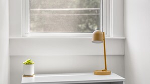 A white shelf with a small potted plant and a floor lamp. - Jungalow Retreat near Swamp Rabbit Trail! (Greenville)