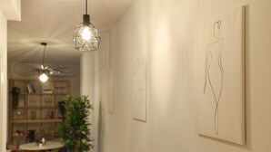 Ein Flur mit Kunstwerken an den Wänden, einem Deckenventilator und einem Essbereich mit Stühlen und einem Tisch.