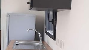 Een moderne keuken met een houten aanrecht, een rvs-spoelbak en zwarte kastjes.
