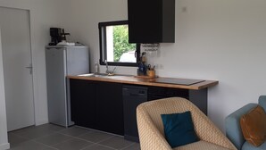 Een compacte keuken met een vaatwasser, een koffiezetapparaat en een raam boven de spoelbak.
