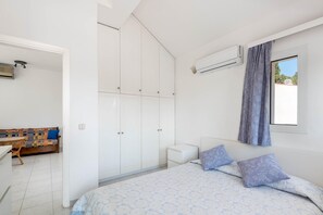 A bedroom with a bed, a wardrobe, a nightstand, and a window with curtains.