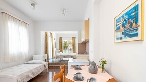 Une pièce avec un lit, une table sur laquelle est disposé un service à thé, un tableau et une vue sur l’extérieur.