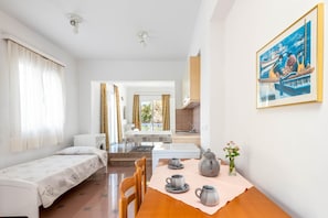 Quarto com cama, mesa com chá, um quadro e vista para o exterior.
