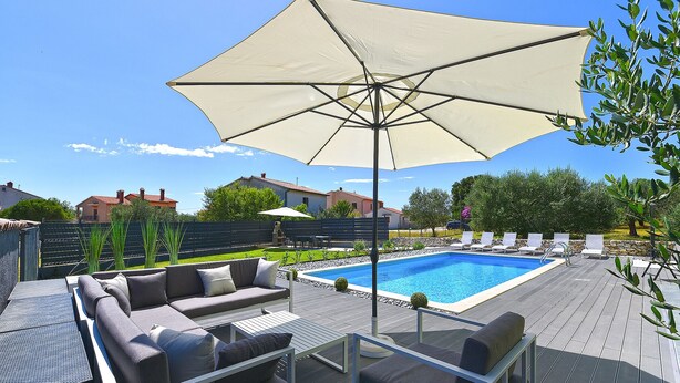 Ein Poolbereich mit Liegestuhl, Sofa und Sonnenschirm.