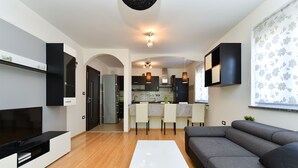 Ein modernes Wohnzimmer mit einem Flachbildfernseher, einem grauen Sofa und einem weißen Couchtisch.