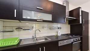 Eine moderne Küche mit dunklen Schränken, einer Edelstahl-Spüle und einem eingebauten Backofen.