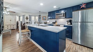 Eine moderne Küche mit blauen Schränken, einem Edelstahlkühlschrank und einer großen Kochinsel mit Spüle.