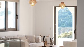 Ein modernes Wohnzimmer mit Sofa, Couchtisch und Dekoration. Große Fenster bieten einen Ausblick ins Freie.