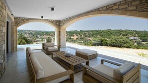 Ein großzügiger Außenbereich mit steinernen Bögen, einem Holztisch und einer Couch, mit Blick auf eine üppige Landschaft.