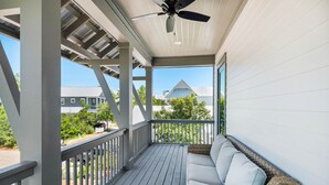 A covered porch with a white railing, a ceiling fan, and a wicker sofa with cushions. - ☀️Spacious Balcony-30A-2 Masters-Bikes-Blue Heron Hideaway (Santa Rosa Beach)