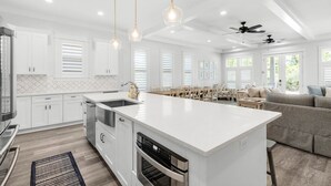 A modern kitchen with white cabinetry, a large island, and pendant lighting. - ☀️Spacious Balcony-30A-2 Masters-Bikes-Blue Heron Hideaway (Santa Rosa Beach)