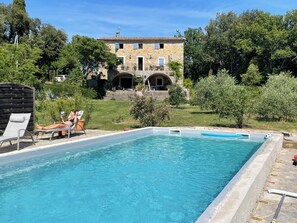 A swimming pool with lounge chairs and a stone building in the background.