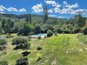 A pool surrounded by lush greenery and trees, with a clear sky above.