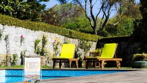 A poolside area with two wooden lounge chairs and a sign indicating Porto was the European Best Destination in 2017. - Garden Pool House by Liiiving (Porto)