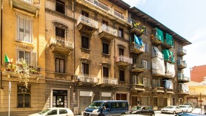 Un edificio a più piani con balconi, un negozio e auto parcheggiate.