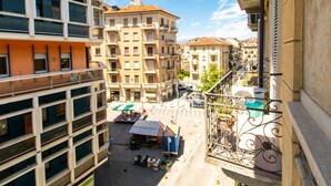 Un edificio a più piani con balconi, un mercato a livello strada e biciclette parcheggiate.