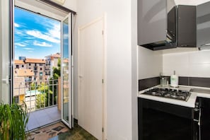A kitchen with a gas stove, a small countertop, and a view of buildings through a glass door.