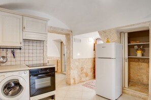 Een functionele keuken met een wasmachine, oven en koelkast.