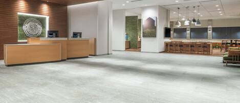A spacious lobby with a reception desk, seating area, and a large wall-mounted artwork.