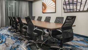 A conference room with a long table and black chairs.