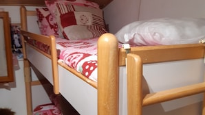 A bunk bed with a wooden frame and a lower bunk with a patterned bedspread. - Apartment 40m2 (La Foux d'Allos)