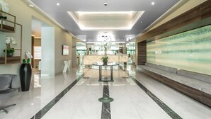 A modern lobby with a reception desk, a large digital display, and a marble floor. - Orbi City Batumi Apartment With sea Views (Batumi)