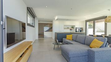 Un salon moderne avec un canapé d’angle gris, un téléviseur à écran plat et un meuble de rangement en bois.
