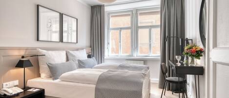 Un dormitorio moderno con cama, mesita de noche, lámpara y ventana con cortinas.