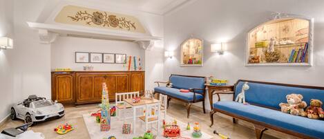 Un salón amplio con techo alto, un aparador de madera, un sofá azul y una variedad de juguetes y juegos infantiles.